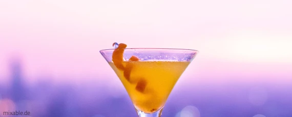Oranger Drink vor pinkem Hintergrund.